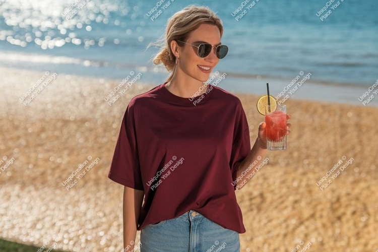 Woman wearing maroon t shirt holding drink on beach