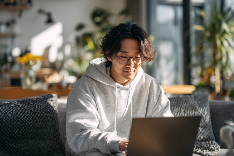 Young Asian man working on laptop in bright, modern home