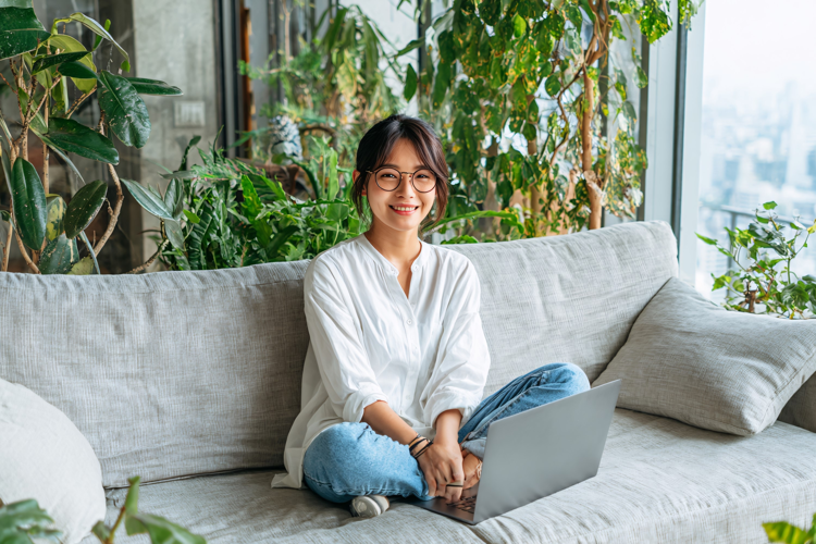 Young Woman Relaxing with Laptop on Sofa
