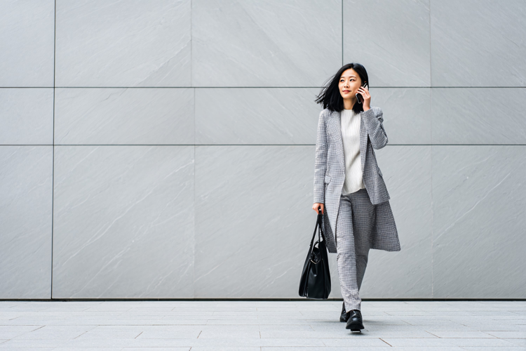 Businesswoman Talking on Phone Walking in Modern City