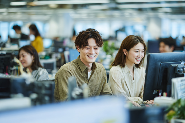 Young Asian professionals smiling working together at comput