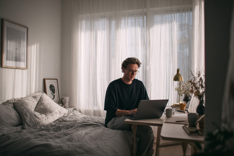 Young Man Working Remotely on Laptop in Cozy Bedroom