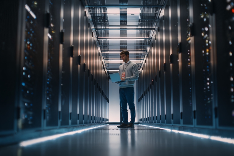 IT Technician Working in Modern Server Room with Laptop Data