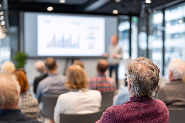 Business Presentation: Audience watches presenter near large