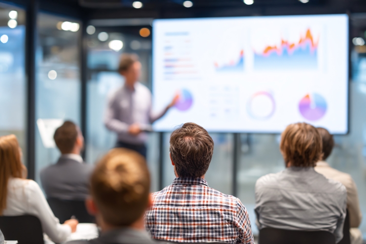 Business Presentation: Speaker Explains Data Charts Screen