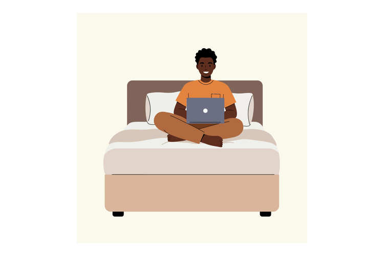 Young man sitting cross-legged on a bed using a laptop in mi