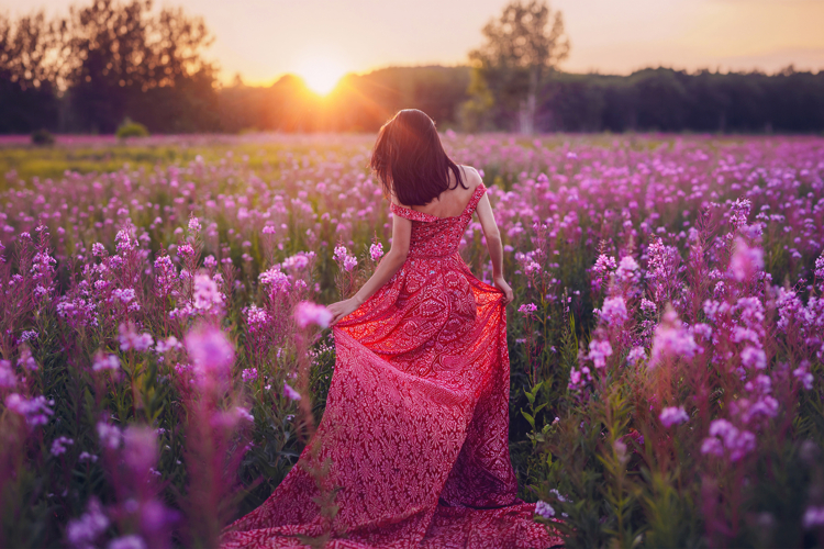Young woman walking through the spring flower field